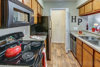 Galley kitchen with electric stove and wood cabinets